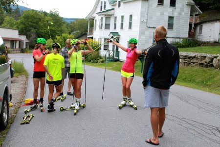 Canadian Globe Cup Group coach Tor-Arne Hetland (r) talks with the SMST2 Staff throughout a water stop on its over-distance rollerski session on Aug. 15 close to Stratton, Vt.